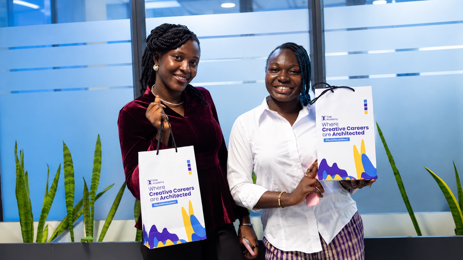 Two TGM Academy Cohort 1 students holding TGM Academy gift bags